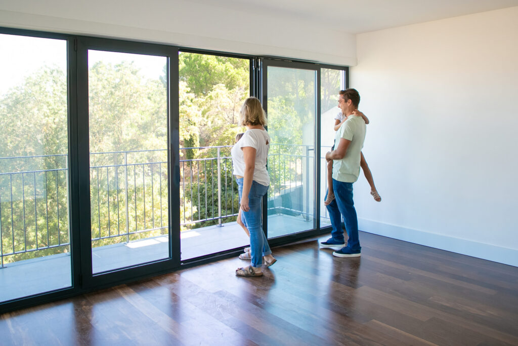 Happy family smiling on a balcony with new glass railing by Groves Glass LLC